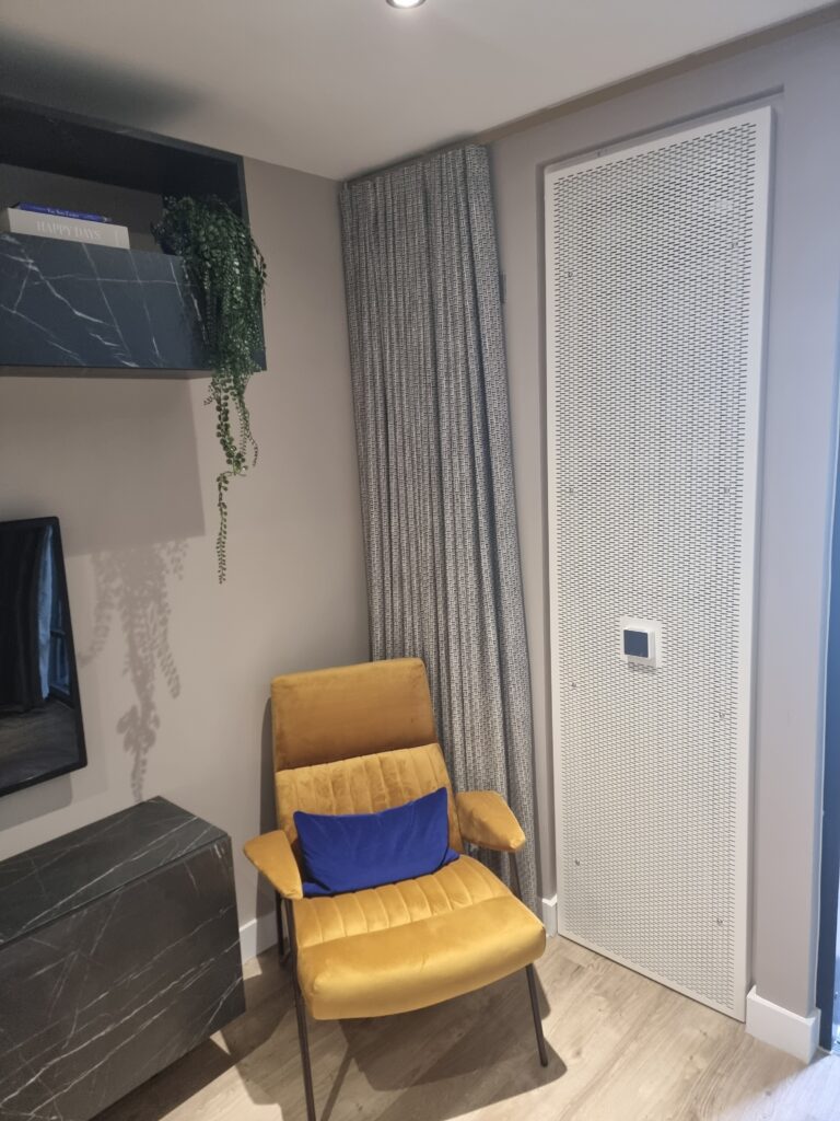 interior photo of an acoustic ventilation system whowing white grille and a control panel