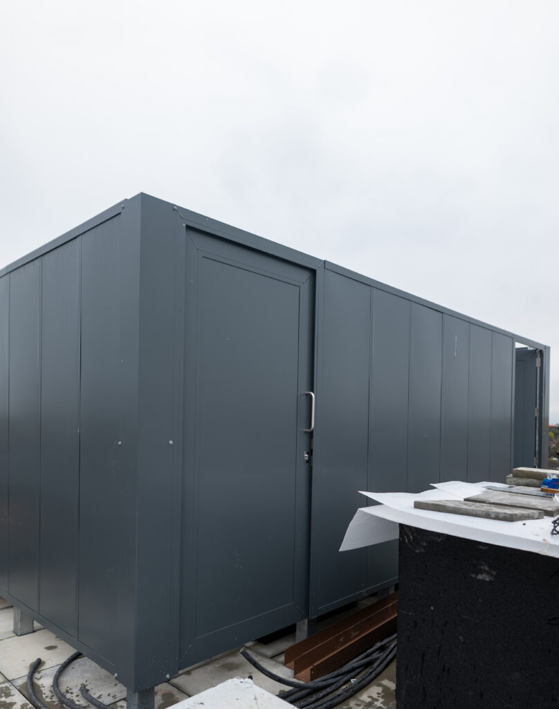 Acoustic enclosures on top of a building around an air source heat pump