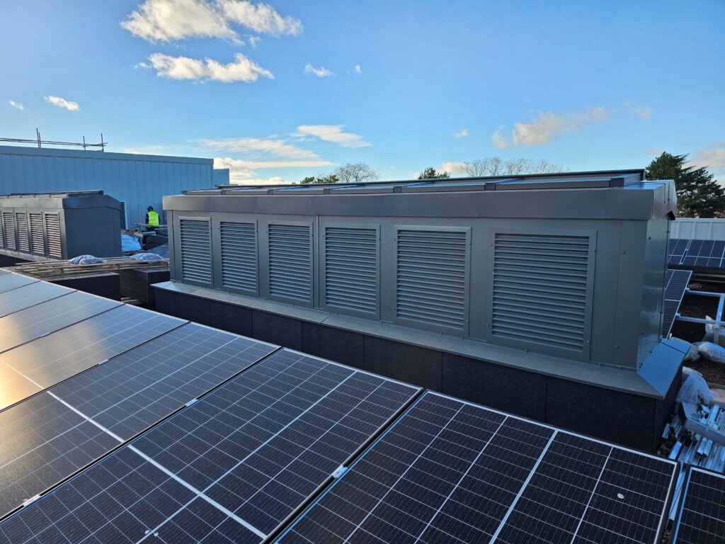 Light stack ventilation unit on top of a school roof with velux rooflights on top to provide natural light to the atrium below. 